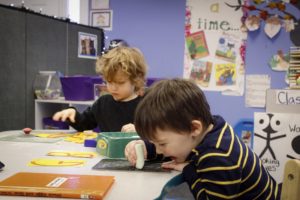 preschool boys in writing area one playing with chalk and theater playing with letters