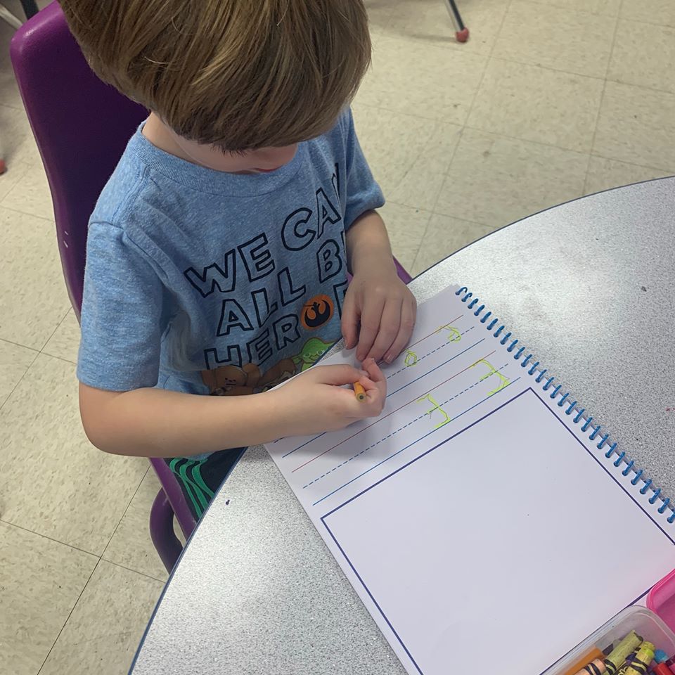 Preschool / Pre-Kindergarten Boy in Blue shirt practicing writing the letter E