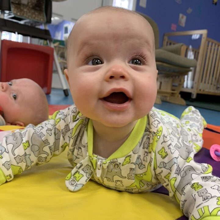 beautiful infant girl smiling on the colorful mats in an elephant onesie